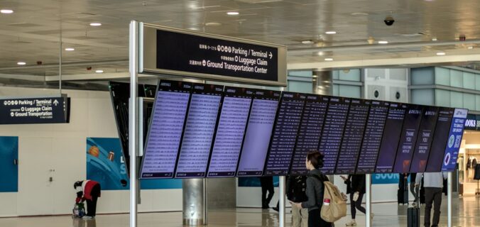 Rejsende med rygsæk kigger på stor afgangstavle i lufthavn